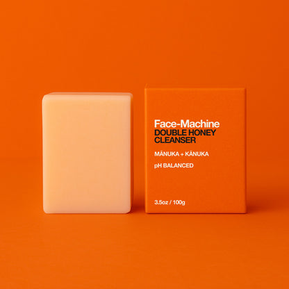 Bar of soap and its packaging on an orange background. Orange box of Face-Machine Double Honey Cleanser on an orange background. facial cleanser, clean skin, skin repair, gift for wife, skincare routine, gentle face wash, hydrating cleanser, anti-aging skincare, daily cleanser, sensitive skin care, skin revitalization, luxury skincare gift, natural cleanser, deep pore cleanse, skin renewal, manuka honey